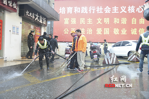 　张贴完春联后，城管工作人员协助环卫工人一起清洗街道。