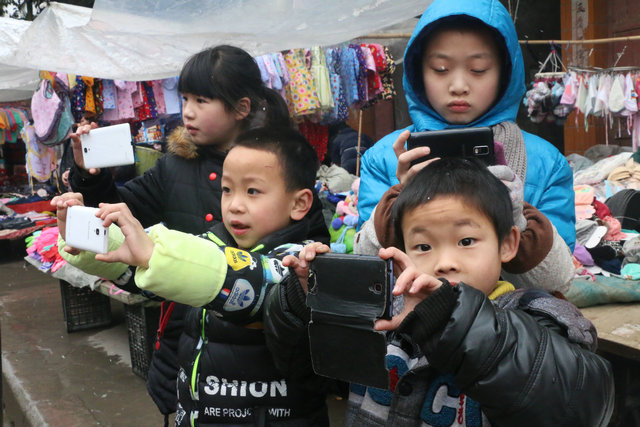 在现场观看绥阳蒲场民俗大“排街”的小朋友们也纷纷拿起手机拍摄留念 （图片由央视网拍客向东提供）