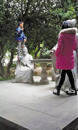 东莞一男童脚踩名人石像拍照