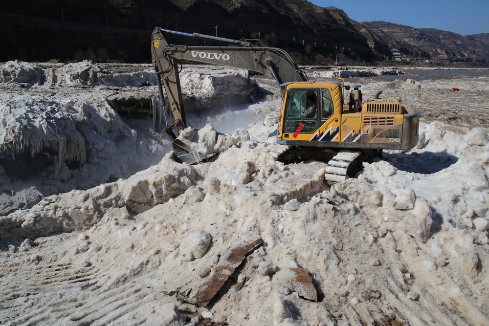2月16日，山西吉县黄河壶口瀑布景区工作人员用挖掘机铲除堆冰。