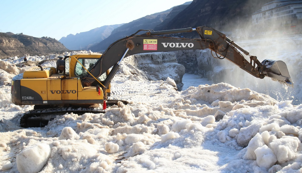 2月16日，山西吉县黄河壶口瀑布景区工作人员用挖掘机铲除堆冰。