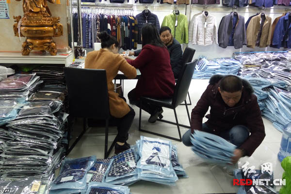 专做男装批发的赵开华一家正在打包着今春的新款衣服。