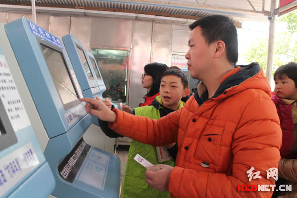 小志愿者在引导旅客使用自助取票机。