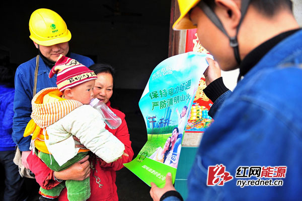 湘潭供电公司输电线路运维员工在市郊双马镇护线网络分布点，向乡镇村民宣传、张贴有关防山火与植树危及电网安全画。