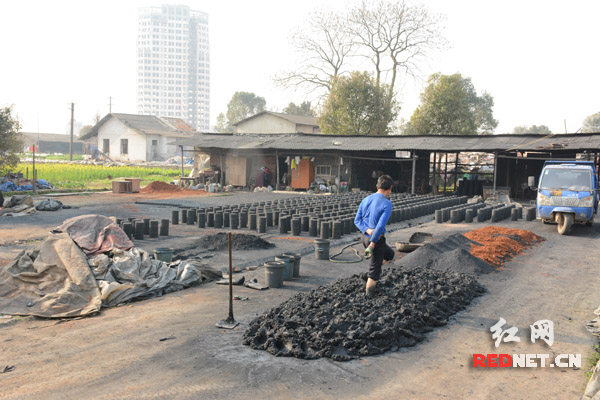 东湖街道合平村一非法生产蜂窝煤的黑作坊，工人在继续加工煤球。