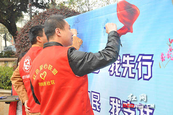 志愿者在“全民城管我先行，城管为民我支持，品质长沙我受益。”的宣传栏上签名。