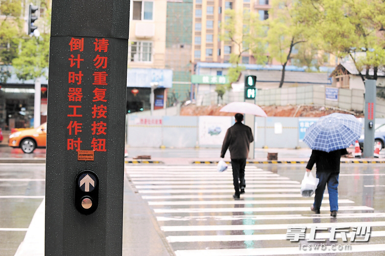 　　图为市民借助行人过街触控式信号灯在雨中从容过马路。 长沙晚报记者 小刘军 摄