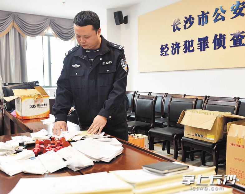 昨日,在长沙市公安局经侦支队,公安民警正在翻看收缴的大量发票。 长沙晚报记者 邹麟 摄
