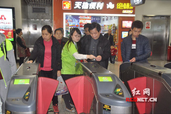 一名乘客在橘子洲站刷卡过关时遇到困难，现场志愿者立刻为其提供帮助。