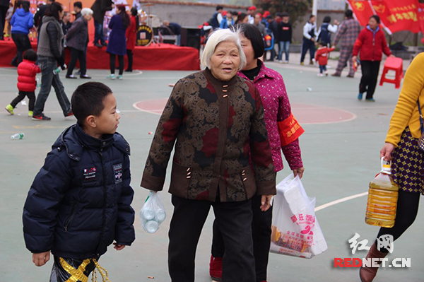 “奶奶，您需要帮助吗？我来帮您拿……”。图为小小志愿者与老人配对，提供贴心服务。