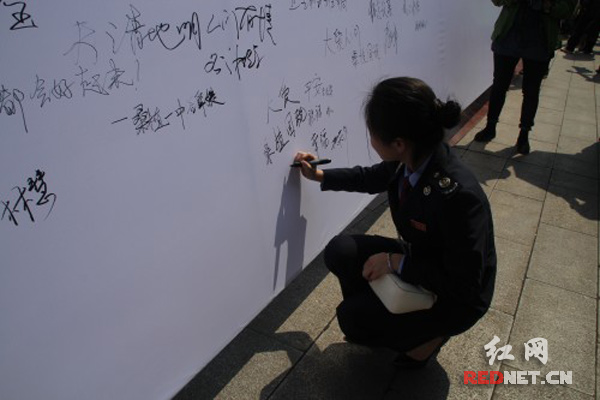 参加爱心活动的国税干部在签名墙上写下爱心宣言。