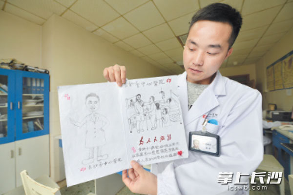 长沙市中心医院医生蒋亮东收到患者家属为自己绘制的漫画，非常开心。 　　长沙晚报通讯员 陈颖 摄