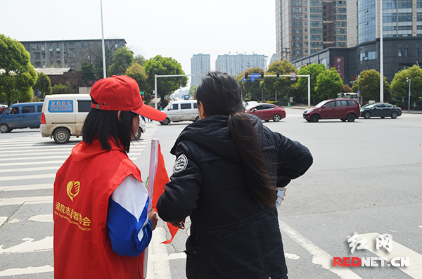 志愿者在十字路口对路人宣传文明交通知识。