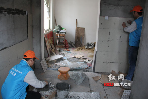 志愿者给湘潭谭新塘里社区贫困老人谭亿芳家贴瓷砖。