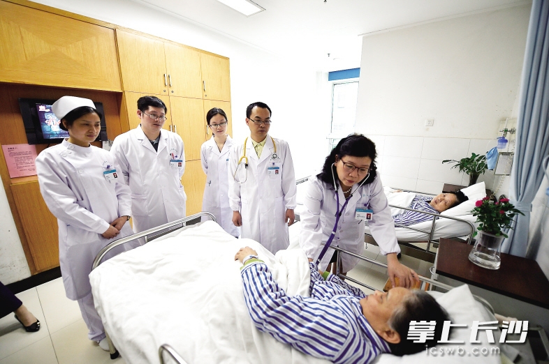 王爱民带领科室医师查房,与患者交流。 长沙晚报记者 余劭劼 摄