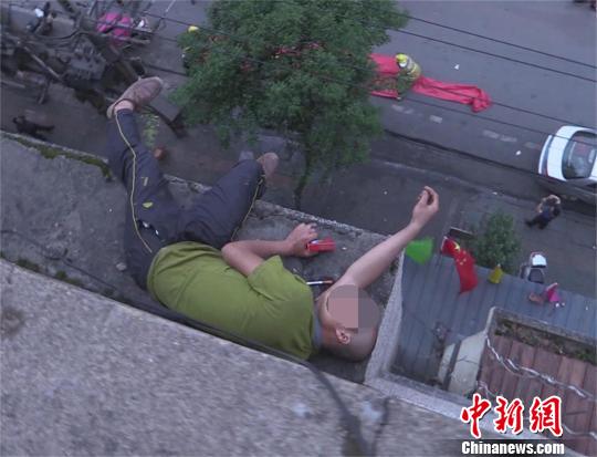 湖北一醉酒男子双脚悬空在楼顶酣睡(图)