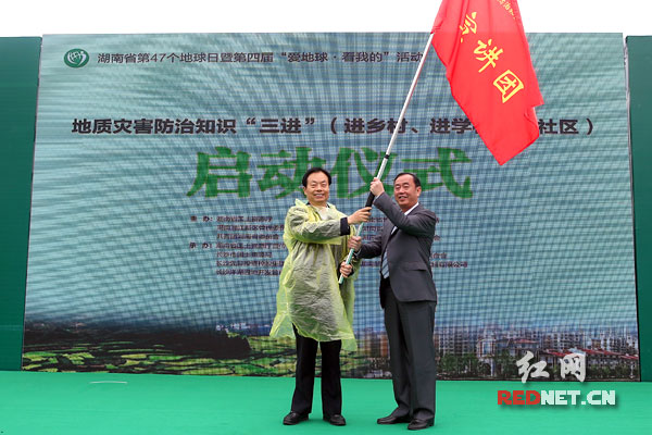 湖南省国土资源厅厅长方先知（左）为地灾防治知识“进乡村、进学校、进社区”宣讲团授旗。