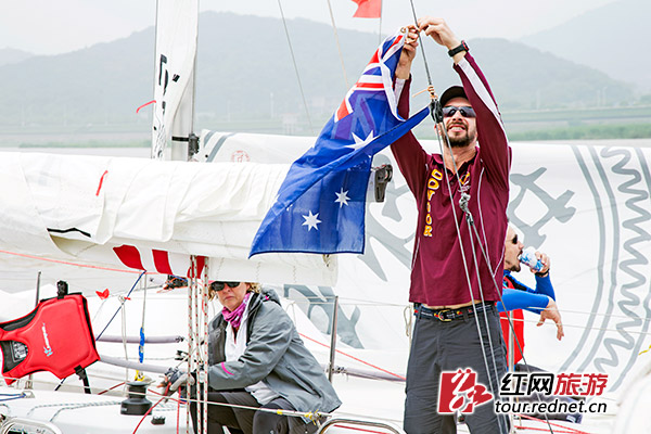 一位选手正往帆船上悬挂国旗。