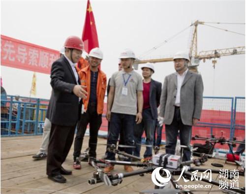 湖南路桥董事长方联民（右一）与大岳高速洞庭湖大桥建设开发有限公司经理梁振西（左一）在架设先导索现场见证