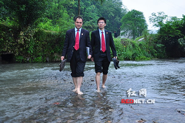 袁占科[左]和同事在办案途中涉水过河。