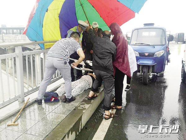 昨日,在长沙湘江橘子洲大桥上,一位老人突然晕倒,呼吸困难,长沙交警和四位新疆大叔,共同救助老人,并拨打了120。通讯员供图