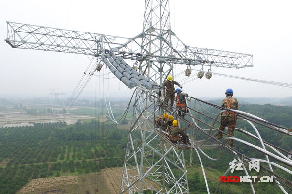 铁塔上的电力施工人员正对接导线。