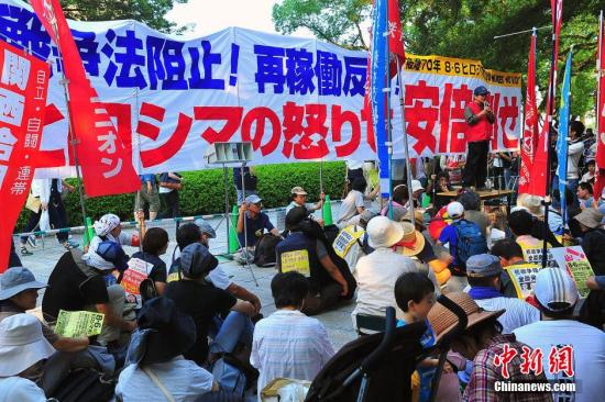 资料图：2015年8月6日，日本广岛遭遇原子弹爆炸70周年。众多市民围坐在离仪式会场不远处的核爆遗址一带，抗议安倍晋安在国会强推旨在解禁集体自卫权的一系列安保法案。 王健 摄