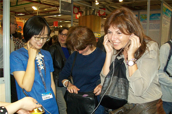 在第115届巴黎国际发明展览会上，两位法国市民对湖南青少年发明的气导型低分贝耳机爱不释手。