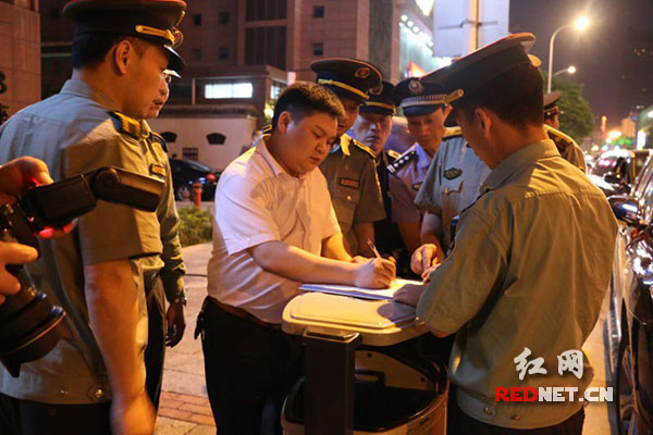 16日晚，夜宵摊主签下“长沙市城市管理综合执法责令限期改正通知书”。