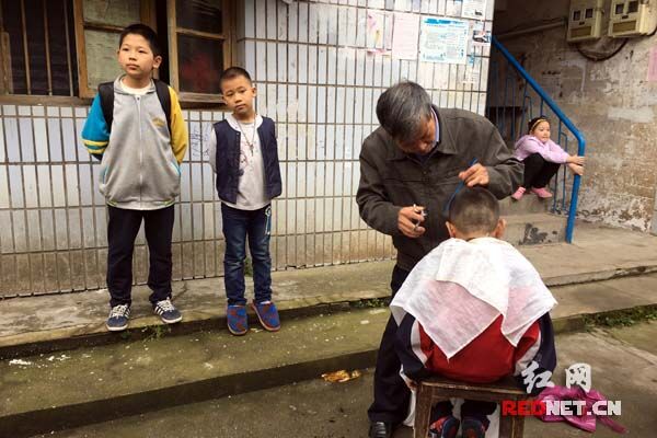 老人和小孩儿是梁志高的主要服务对象。图为他正在为邻居小孩理发。
