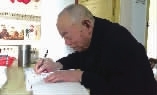  八十四岁的老党员粟福兴在家抄写《党章》。