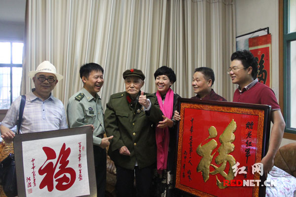 两位民间艺人的作品让老红军张生荣（左三）竖起大拇指。