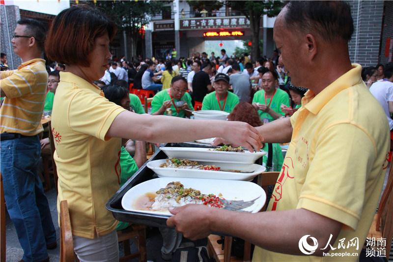 工作人员为游客端来一盘盘鲜鱼