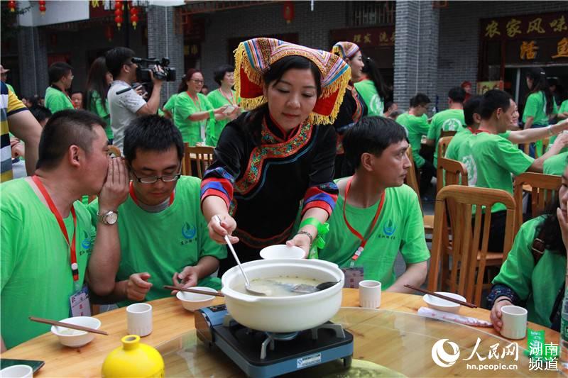 热情的瑶族姑娘为远道而来的客人盛上一碗鱼汤
