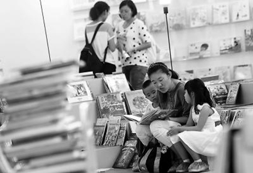 一位妈妈在图书博览会现场为小朋友阅读绘本。记者孙戉摄图片来源:北京日报