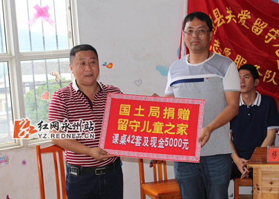 道县国土资源局党组成员、副局长张尚明(左二)代表该局向道县横岭乡中心小学留守儿童之家资助课桌42套、现金5000元。