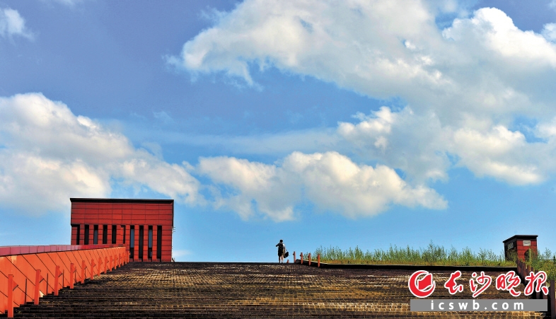 　　一位游客走在湘江风光带台阶上，好像要去触摸这天空的云朵。 