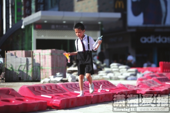 手拿奖状的小男孩从地铁1号线黄兴广场站2号出入口附近侧倒的护栏上经过。
