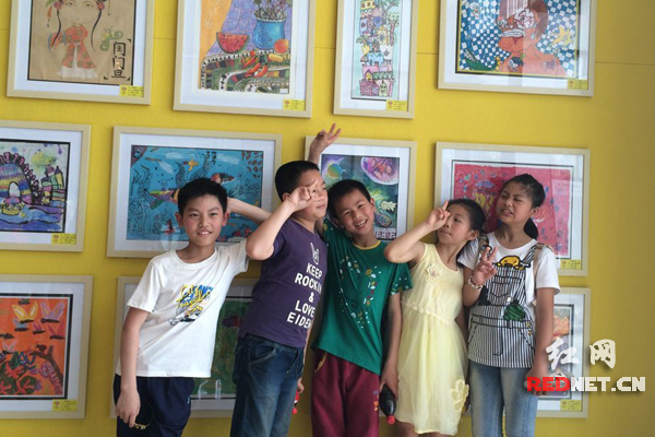 6月1日上午10:15，长沙德思勤广场，五个小孩在的一块画展前开心地拍照合影。