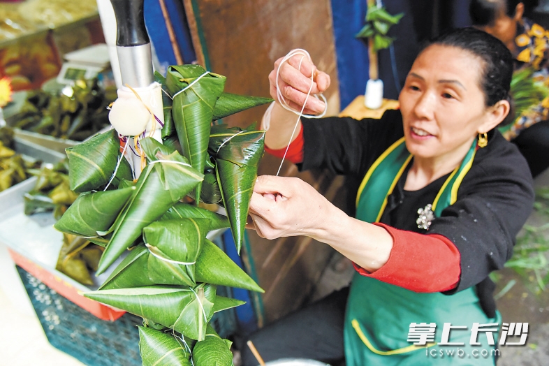 　　粽子是端午的节物。这是来自桃江、50岁的王培云在长沙一家小店内包粽子。包粽子的传统因为传承而不会绝灭。