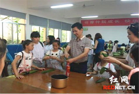 株洲县文体广新和旅游局副局长许建勇教小朋友包粽子。