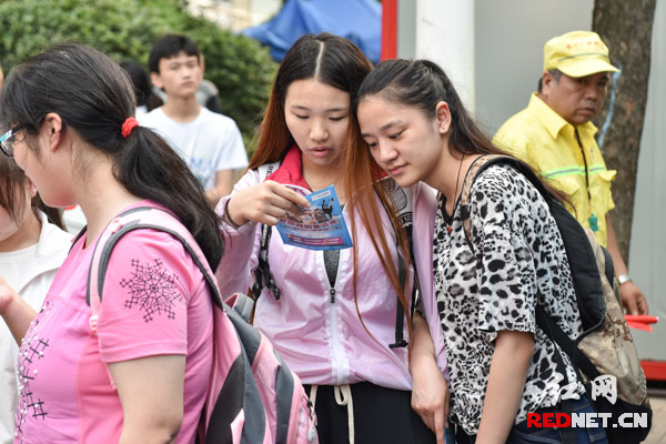 两个身材高挑的女生正在仔细看一个舞蹈培训的宣传单。