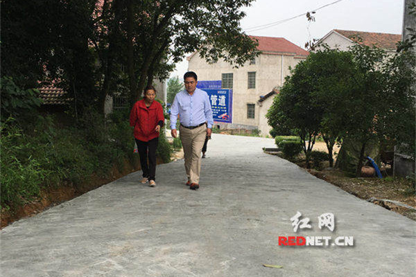 蒋小毛来到湖头村刚修好的一条水泥路上,提醒附近村民别忘了给新修的路施一些水。