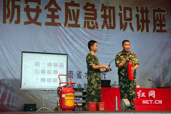 消防大队教官演示讲解灭火器的使用方法。
