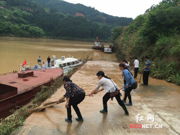 江华县党员服务队在涔天河镇暴雨受灾地区务江渡口开展灾后清扫工作。