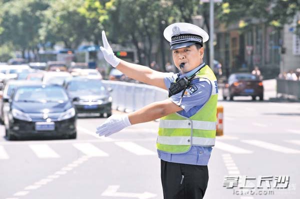 顶着烈日，刘辉在路口打出精准而有力的交通指挥手势。长沙晚报记者小刘军摄