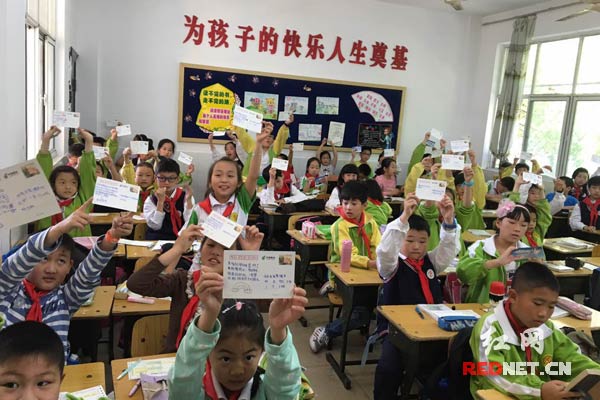 常德邮政组织北正街小学学生亲手为结对帮助的农村留守儿童写邮政明信片。