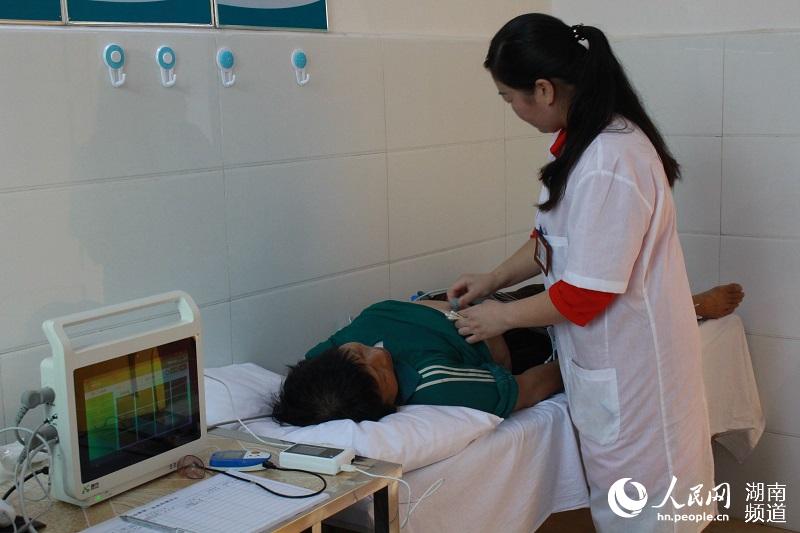 卫生室里，村医张卫红正在使用一体机为村民检查身体