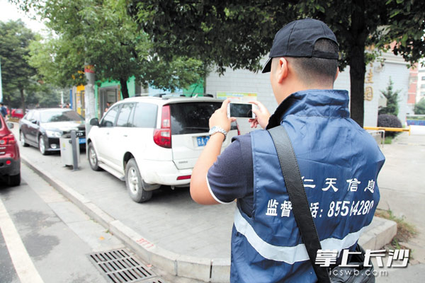 一位数字化城管信息采集员正对街边人行道上乱停车现象进行拍照取证，然后上传。长沙晚报记者 陈飞 摄
