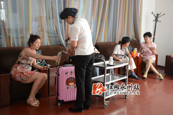 工作人员为在商务候车室内休息的旅客添茶加水。